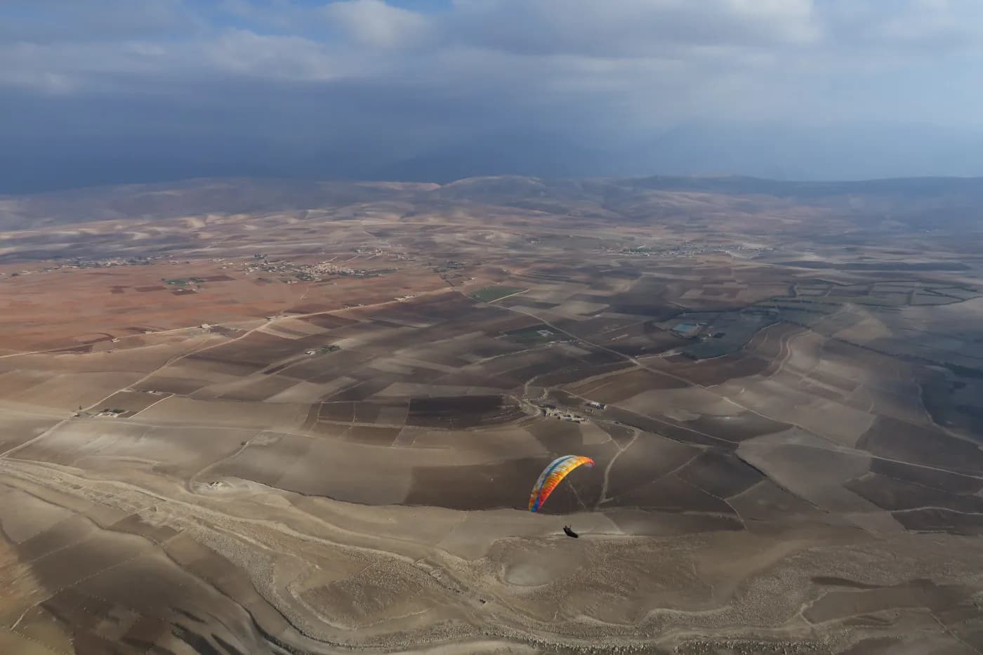 Paraglider flying over Aguergour, view over the northern ridge, Morocco